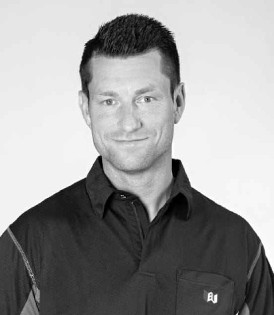 A man with short hair wearing a dark collared shirt, smiling slightly, in a black and white photo.